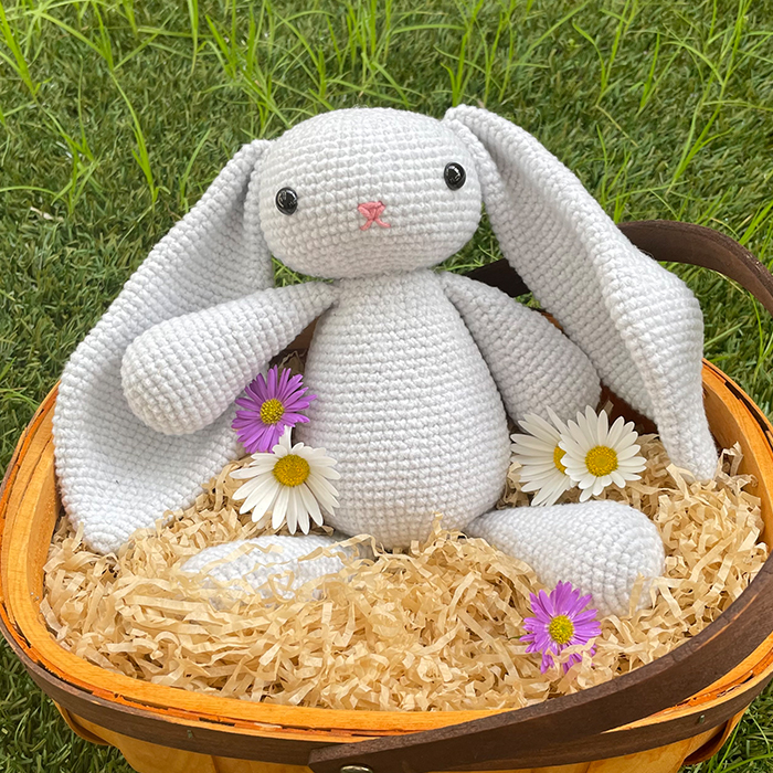 floppy bunny amigurumi in basket with shredded paper and flowers